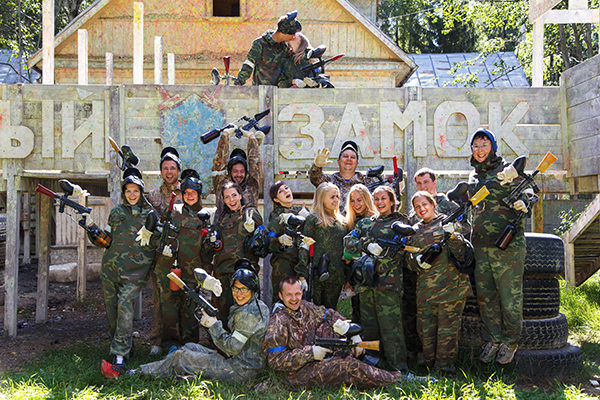 Group portrait of big happy company playing paintball